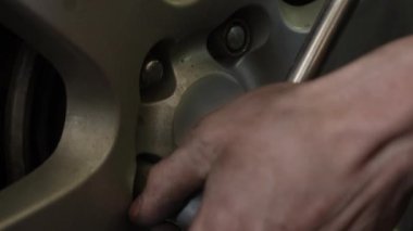 Bir arabanın lastiklerini değiştirmek. Tekerlek anahtarıyla cıvataları sıkan bir adam. Otomobil tamircisi elleri yakın çekim. Yüksek kalite 4k görüntü