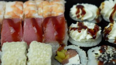 Sushi dürümleri yakın plan. Pirinç, kaplan karidesi, somon, ton balığı, yılan balığı. Lezzetli taze Japon yemekleri. Deniz ürünleri. Suşi rulosu reklamı. Üst Manzara. Yüksek kalite 4k görüntü