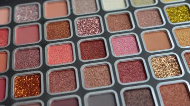 Rengarenk göz farı paleti. Gölgelerin parlak ve değişik tonlarında, mat ve parlak. Profesyonel göz estetiği. Kapatın. Dairesel dönüş. Ağır çekim. Yüksek kalite 4k görüntü