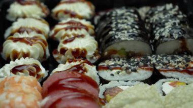 Pirinç, kaplan karidesi, somon, ton balığı, yılan balığı, susam, krem peynir ve sos ile iştah açıcı rulo. Farklı şekillerde ve tiplerde suşi ruloları. Lezzetli çiğ Japon yemekleri. Deniz ürünleri. Üst Manzara. Yakın plan.