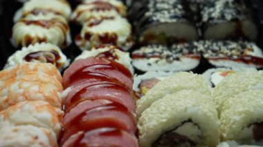 Sushi dürümleri yakın plan. Pirinç, kaplan karidesi, somon, ton balığı, yılan balığı. Lezzetli taze Japon yemekleri. Deniz ürünleri. Suşi rulosu reklamı. Üst Manzara. Kabloları kapat.