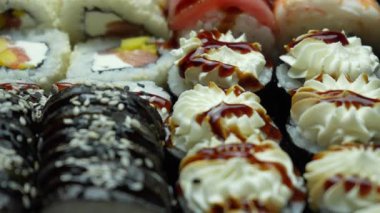 Pirinç, kaplan karidesi, somon, ton balığı, yılan balığı, susam, krem peynir ve sos ile iştah açıcı rulo. Farklı şekillerde ve tiplerde suşi ruloları. Lezzetli çiğ Japon yemekleri. Deniz ürünleri. Üst Manzara. Yakın plan.