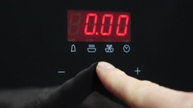 Mikrodalga fırının dijital görüntüsünü ayarlayan bir elin yakın çekimi. İşaret parmağı elektronik panelde zamanlayıcıyı ayarlıyor, zamanı kırmızı gösteriyor... 4K 'lık yüksek kaliteli görüntü.