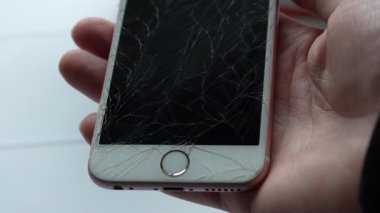 Görünürde çatlak bir ekranla akıllı telefonu tutan bir kişinin yakın çekimi cihazın durumunu vurguluyor. Hasar nedeniyle onarılması ya da yenilenmesi gerektiğini gösteriyor. Tam HD görüntüler