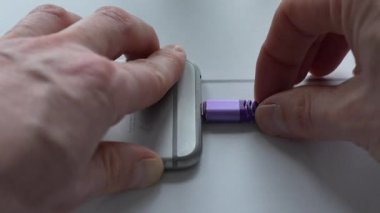 Masadaki bir cihaza mor bir USB kablosu sokan elin yakın görüntüsü. Görüntü teknolojiyi birleştirme eylemini vurguluyor, ellere ve USB bağlantı sürecine odaklanıyor. Tam HD görüntüler