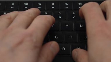 Siyah dizüstü bilgisayar klavyesinde daktilo eden düzgün bir erkek eli. Yakın çekim, üst görüş. Yüksek kalite 4k görüntü