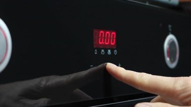 Mikrodalga fırının dijital görüntüsünü ayarlayan bir elin yakın çekimi. Erkek işaret parmağı elektronik paneldeki zamanlayıcıyı ayarlar, 0: 05 'i kırmızıyla gösterir. Yüksek kalite 4k görüntü
