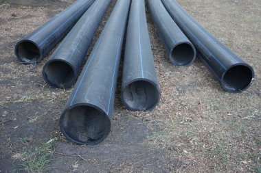 Yerde kurulum için bekleyen birkaç büyük siyah plastik boru var. Açık hava inşaatı ya da altyapı projesi. Yüksek kalite fotoğraf