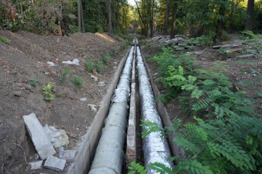 Şehir ısıtma altyapısının bir parçası olan siperdeki termal yalıtımlı boru hatlarının dış görünüşü. Dışarıdaki siperde termal yalıtımlı borular.
