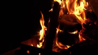 Açık hava ızgarasında parlak bir alev ve karanlıkta parlayan kütükler. Kamp, barbekü, sıcaklık, rahatlama ya da rahat bir arka plan için atmosferik ateş..