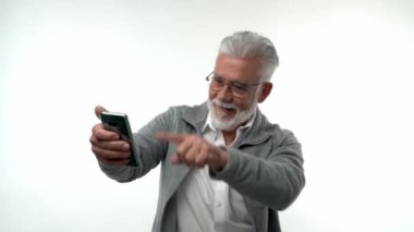 Yaşlı adam akıllı telefonla poz veriyor, yaşlılar için büyük ticari teklifler alan SMS 'leri okuyor başarıyı sevinçle, samimi duygularla, fırsat konseptiyle kutluyor. Bir parmak ile noktalar.