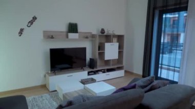 Kanepesi, televizyonu ve loş ışıkta modern dekorasyonu olan bir oturma odasının video görüntüleri. Hareket halindeyken çekiyoruz. Yüksek kalite 4k görüntü