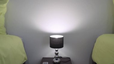 Komodinli modern yatak odası. Geceleri masa lambasını yakardı. Havlular yatağın üstünde. Yüksek kalite 4k görüntü