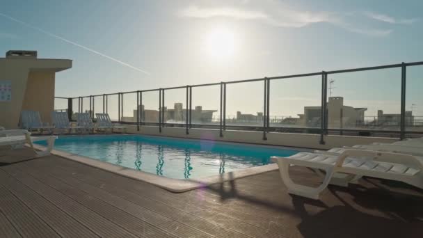 ホテルの屋根の上に青い水でプール 観光客のためのサンラウンジャー — ストック動画