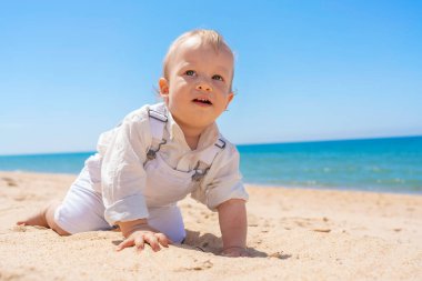 Küçük bir çocuk kumsalda kumda sürünüyor. Güneşli bir gün. Yüksek kalite fotoğraf