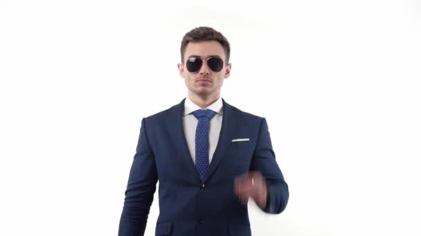 スローモーションの若い男性実業家は 遠くを見て 自分自身に自信を持って 彼のサングラスを調整します 白い背景で 高品質のフルHd映像 — ストック動画