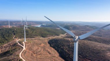 Wind turbines generate clean, green electricity in the fields of Portugal. With a view of the Bravura dam. High quality photo