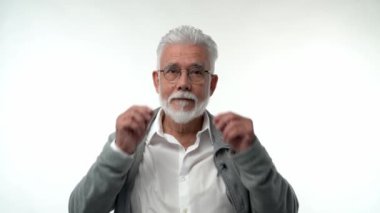 Portrait of an elderly retired man in glasses talking on a mobile phone on a white background. Gray-haired grandfather with a beard posing on an isolated studio background. Slow motion. High quality