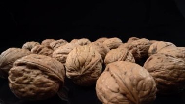 Lots of whole walnuts in extreme macro shot. On a black background. High quality 4k footage