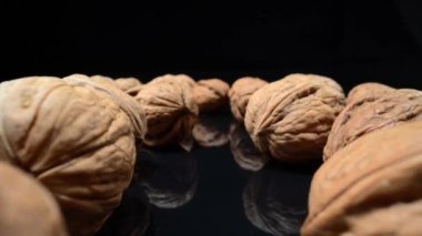 Lots of whole walnuts in extreme macro shot. On a black background. High quality 4k footage