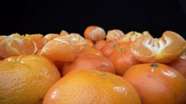 Lots of ripe tangerines shot in extreme detailed macro. On a black background. High quality 4k footage