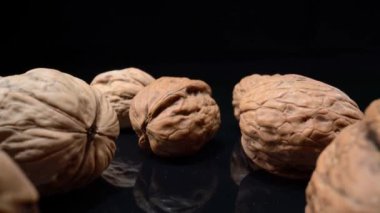 Lots of whole walnuts in extreme macro shot. On a black background. High quality 4k footage