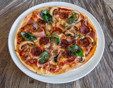 Fresh pizza with spinach jamon and mushrooms on a wooden background close-up. High quality photo
