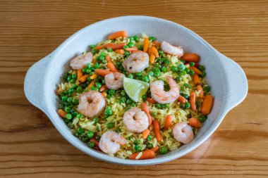Appetizing oriental healthy salad of boiled squid, rice, green peas and other ingredients on a plate on a wooden background. High quality photo