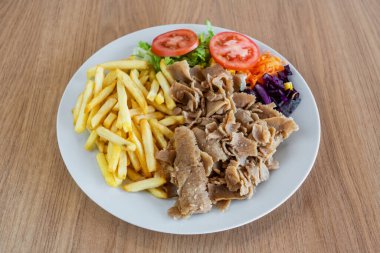 Kebab on a plate with fried potato salad and vegetables