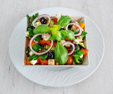 Salad with cheese and fresh vegetables isolated on white background. Greek salad in a plate on a white wooden background. High quality photo