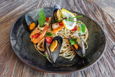 Seafood, mediterranean cuisine. Spaghetti with squid, clams oysters shrimp and herbs. High quality photo