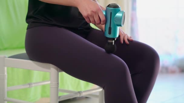 女运动员使用现代按摩枪治疗大腿松弛 训练后运动康复的概念 高质量的4K镜头 — 图库视频影像