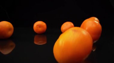 Fresh yellow falling tangerines on a black background in slow motion. High quality FullHD footage