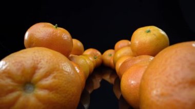 Lots of ripe tangerines shot in extreme detailed macro. On a black background. High quality 4k footage