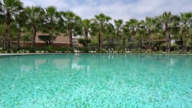Beautiful hotel for relaxation with a swimming pool with blue turquoise water. Lawn with palm trees. High quality 4k footage