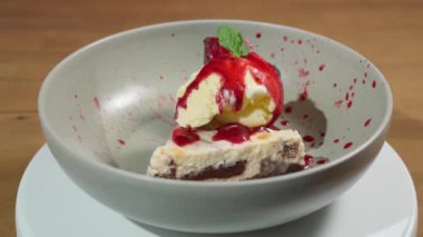 Beautiful pieces of cake decorated with ice cream on a rotating plate. Fruit syrup. Close-up. Slow motion. High quality FullHD footage