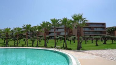 Hotel with swimming pool with clear blue water with palm trees. High quality 4k footage