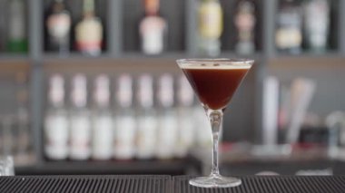 Bir kadının eli bardan bir bardak espresso martini alır. Arka plan bulanık. Yüksek kaliteli FullHD görüntüler