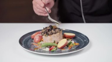 Şef sosu bir restoran yemeğinde müşteriler için gurme balık ve sebze filetosunun üzerine döker. Yüksek kaliteli FullHD görüntüler