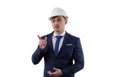 A handsome man in a suit and helmet shows the emotions of solving the problem by pointing with his index finger. Concept in the studio on a white background. High quality photo
