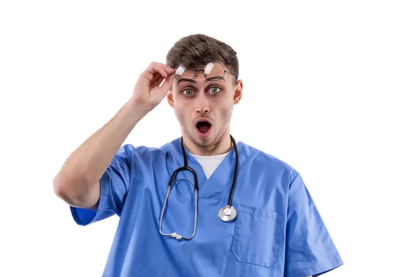 均一で聴診器を持つ医師は 口を開けて眼鏡を上げることによって驚きと恐怖の感情を示しています 高品質のフルHd映像 — ストック写真