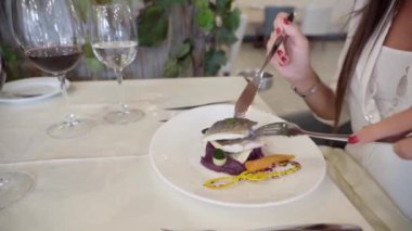 Şık bir restorandaki VIP müşteriler garnitürlü balık ve çatallı sebze yerler. Turizm eğlencesi ve gastronomi konsepti. Yüksek kaliteli FullHD görüntüler