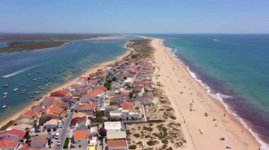 Okyanus kıyısının ve plajın havadan görünüşü. Sudaki tekneler ve kumsalda dinlenen turistler bir İHA 'dan görüldüğü gibi. Praia de Faro Algarve Portekiz. Yüksek kalite 4k görüntü