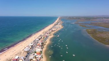 Okyanus kıyısının ve plajın havadan görünüşü. Sudaki tekneler ve kumsalda dinlenen turistler bir İHA 'dan görüldüğü gibi. Praia de Faro Algarve Portekiz. Yüksek kalite 4k görüntü