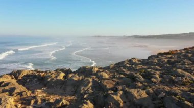 Portekiz 'de güneş doğarken Praia do Malhao sahilinin sisli ve sisli görüntüsü. Yüksek kalite 4k görüntü