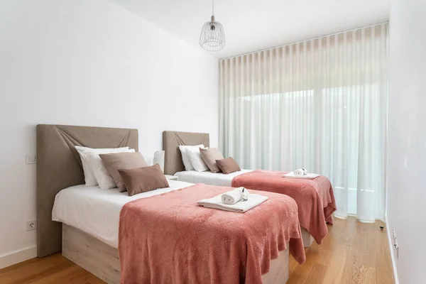 Double bed in the bright bedroom room interior furnishing furniture. With a red blanket and white towels on a roll. High quality photo