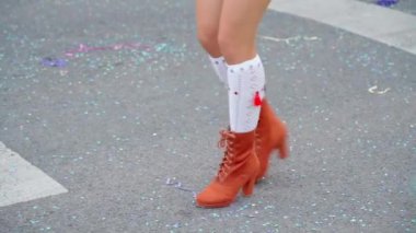 Kadınların zarif bacakları ve güzel ayakkabıları. Eğlenceli bir karnavalda ağır çekimde samba ve yerde konfeti dansı yapıyorlar. Yakın plan. Yüksek kaliteli FullHD görüntüler