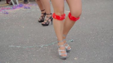 Kadınların zarif bacakları ve güzel ayakkabıları. Eğlenceli bir karnavalda ağır çekimde samba ve yerde konfeti dansı yapıyorlar. Yakın plan. Yüksek kaliteli FullHD görüntüler