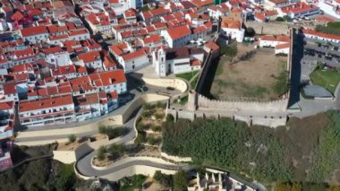 Atlantik kıyısındaki eski Portekiz Sines kasabasının insansız hava aracı görüntüleri. Kilisenin çatıları ve yılan yolu manzaralı.
