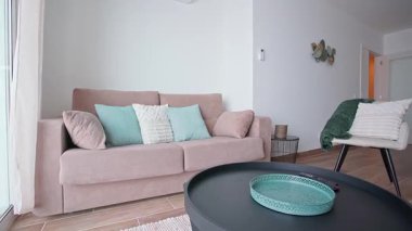 Minimalist oturma odasında pastel yastıklı bej bir kanepe. Açık renkli duvarlar ve yumuşak dokular rahat ve şık bir iç mekan oluşturur. Modern ev konforu ve rahatlama kavramı